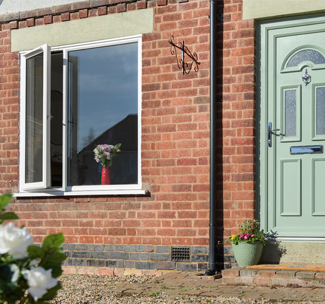White uPVC casement window with sage green front door